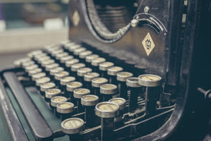 Close-up view of vintage typewriter keys, showing metal rims and raised round buttons in an old-fashioned, mechanical design.